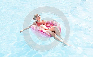 Woman relaxing on donut lilo in the pool at private villa. Inflatable ring and mattress. Summer holiday idyllic. High