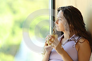 Woman relaxing drinking coffee looking through a window