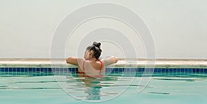 Woman relaxing at the edge of swimming pool in the backyard at home