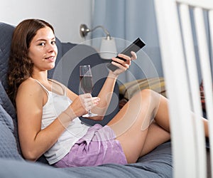 Woman relaxing at evening with glass of red wine on sofa