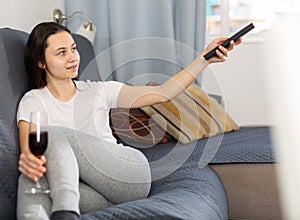 Woman relaxing at evening with glass of red wine on sofa
