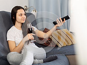 Woman relaxing at evening with glass of red wine on sofa