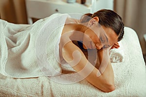 Woman relaxing with eyes closed, enjoying professional massage at spa center