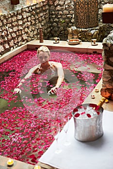 Woman Relaxing In Flower Petal Covered Pool At Spa