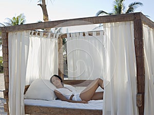 Woman Relaxing In Four-Poster Bed