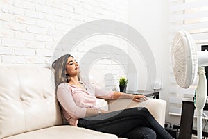 Woman Relaxing In Front Of Fan During Summer At Home