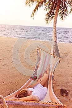Woman relaxing in a hammock on a beach