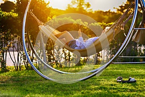 Woman relaxing in a hammock in the garden at sunset