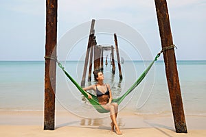 Woman is relaxing in the hammock hanging on old beams from the broken pier