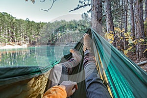 Woman relaxing in the hammock by the lake