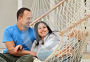 Woman relaxing in hammock smiling and man sitting