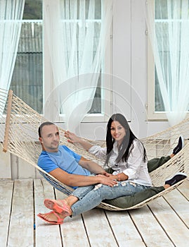 Woman relaxing in hammock smiling and man sitting