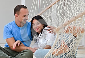 Woman relaxing in hammock smiling and man sitting