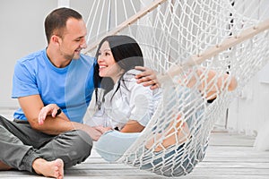 Woman relaxing in hammock smiling and man sitting