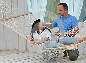 Woman relaxing in hammock smiling and man standing