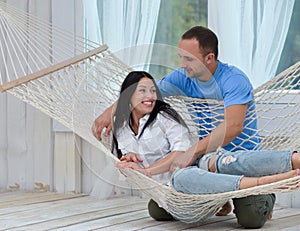 Woman relaxing in hammock smiling and man standing