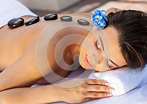 Woman Relaxing At Health Spa Having Hot Stone Treatment Massage