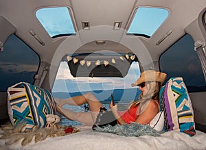 Woman relaxing in her van using mobile phone