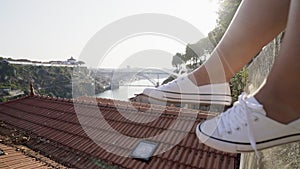 Woman relaxing on high top wall above city