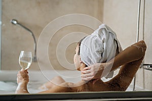 Woman relaxing at home in the hot tub bath ritual,drinking wine.Relaxing spa night in bathroom.Good personal hygiene routine.Skin,