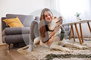 Woman relaxing at home hugging and cuddling her dog