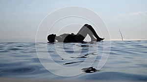 Woman relaxing in infinity swimming pool looking at view