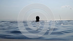 Woman relaxing in infinity swimming pool looking at view