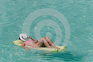 Woman relaxing on inflatable air mattress at turquoise water