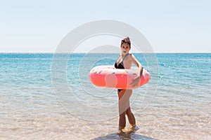 Woman relaxing with inflatable ring on the beach. shocked or surprised girl in the cold sea. Summer holidays and vacation concept