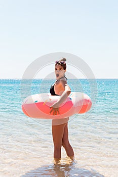 Woman relaxing with inflatable ring on the beach. shocked or surprised girl in the cold sea. Summer holidays and vacation concept