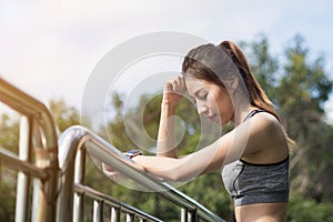 Woman relaxing after jogging exercise on fence at park to freshen her body.