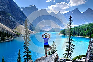 Woman relaxing by lake and mountains.