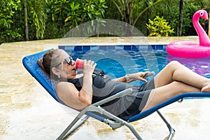 Woman relaxing in lounge chair at pool