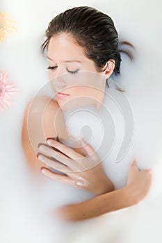 Woman relaxing in milk bath with flowers