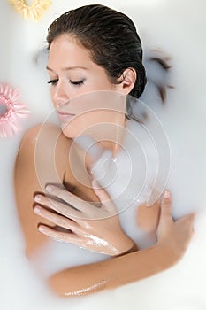 Woman relaxing in milk bath with flowers