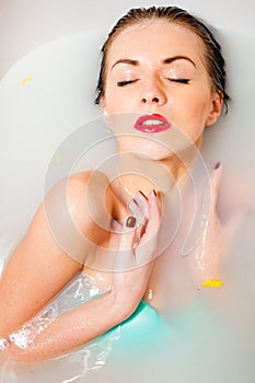 Woman relaxing in milk bath with flowers