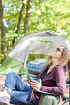 Woman relaxing with a mug of coffee in morning at campsite in fa