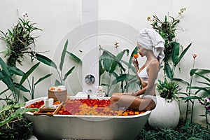 Woman relaxing in outdoor bath with flowers in Bali spa hotel