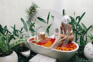 Woman relaxing in outdoor bath with flowers in Bali spa hotel