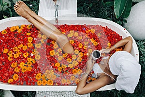 Woman relaxing in outdoor bath with flowers in Bali spa hotel