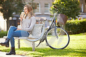 Woman Relaxing On Park Bench With Takeaway Coffee