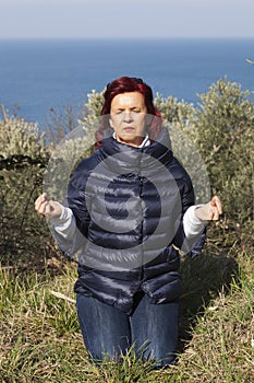 Woman relaxing, performing joga on sea coast