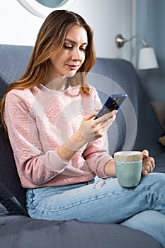 Woman relaxing with phone on sofa at home
