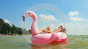 Woman relaxing on a pink flamingo mattress