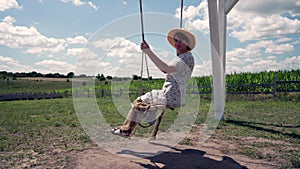 Woman relaxing on a rural swing in evening light