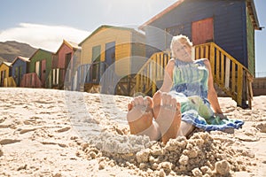 Woman relaxing on sand against huts at beach