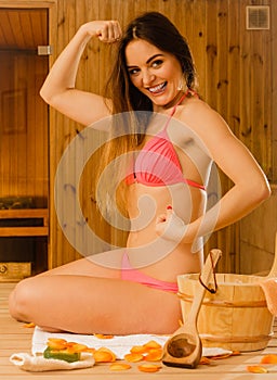 Woman relaxing in sauna showing off muscles.