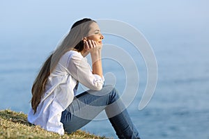 Woman relaxing sitting on the grass watching the sea