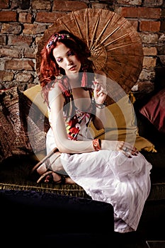 Woman relaxing on sofa holding japanese parasol