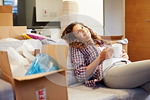 Woman Relaxing On Sofa With Hot Drink In New Home